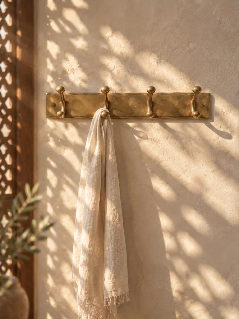 Solid brass hook rack on a lime plaster wall in Marrakech light